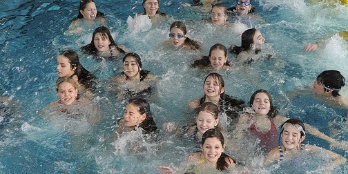 Viele Kinder schwimmen im Wasser des Freiberger Hallenbades.